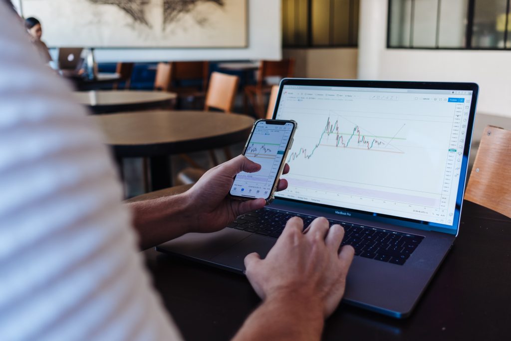 Personne consultant des graphiques financiers sur smartphone et ordinateur, usage typique de la fintech