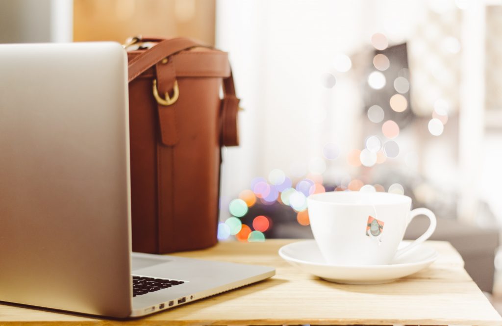 Ordinateur portable, sacoche en cuir et tasse de café sur un bureau, prêts pour la rentrée