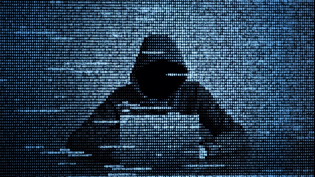 Pirate informatique encapuchonné devant un ordinateur, sur fond de code